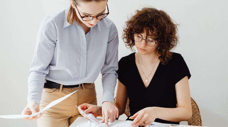 Two Women Looking at White Paper